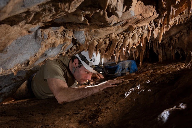 Tác giả Neil Shea lách qua một lối đi để vào một hang động vô danh mà nhóm chỉ vừa khám phá ra vài ngày trước.