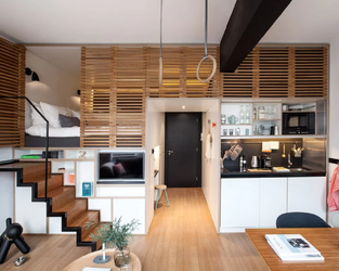 Khu vực ngủ trên bục gỗ tích hợp lưu trữ ẩn và tủ kịch trần trong căn hộ Studio 30m²