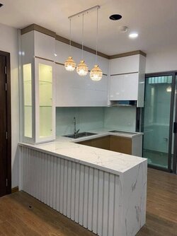 Bếp chữ I nhỏ gọn, sử dụng tông màu trắng và bàn đảo kiêm bàn ăn trong thiết kế căn hộ Studio 30m²