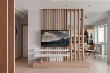 Tận dụng vách ngăn hở hoặc kệ trang trí hai mặt để tạo ranh giới ảo, giúp tối ưu hóa không gian phòng khách và bếp chung cư.